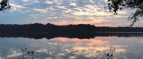 Foto met zicht op Carptwenty an hengels in het water bij zonsondergang